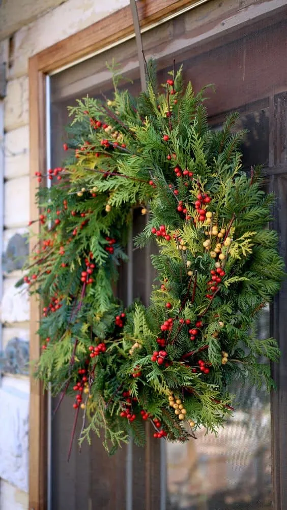 Klassische Weihnachtskrone mit grünem Grünzeug und Beeren Traditionelle Weihnachtskrone mit roten Beeren und frischem Grünzeug
