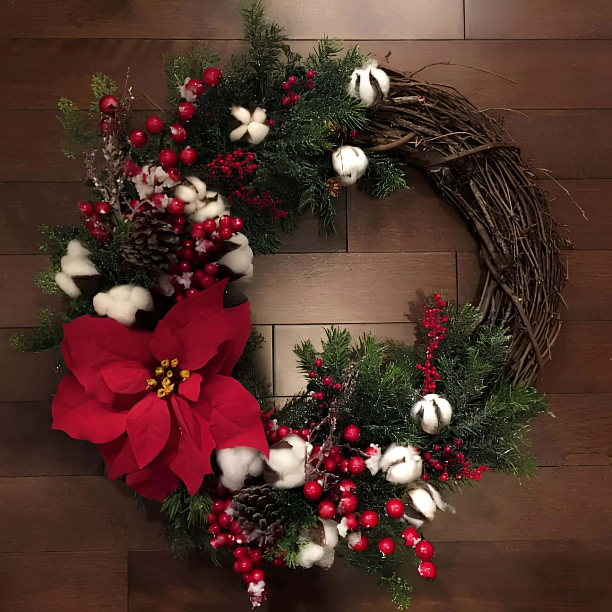 Weihnachtskranz mit Poinsettia, Baumwollbällen, Beeren, Kiefernzapfen und Grünpflanzen sowie Schleife Kranz aus Reben mit einer roten Poinsettia, Baumwollbällen, Beeren, Kiefernzapfen und Grünpflanzen, zusammengebunden mit einer Schleife