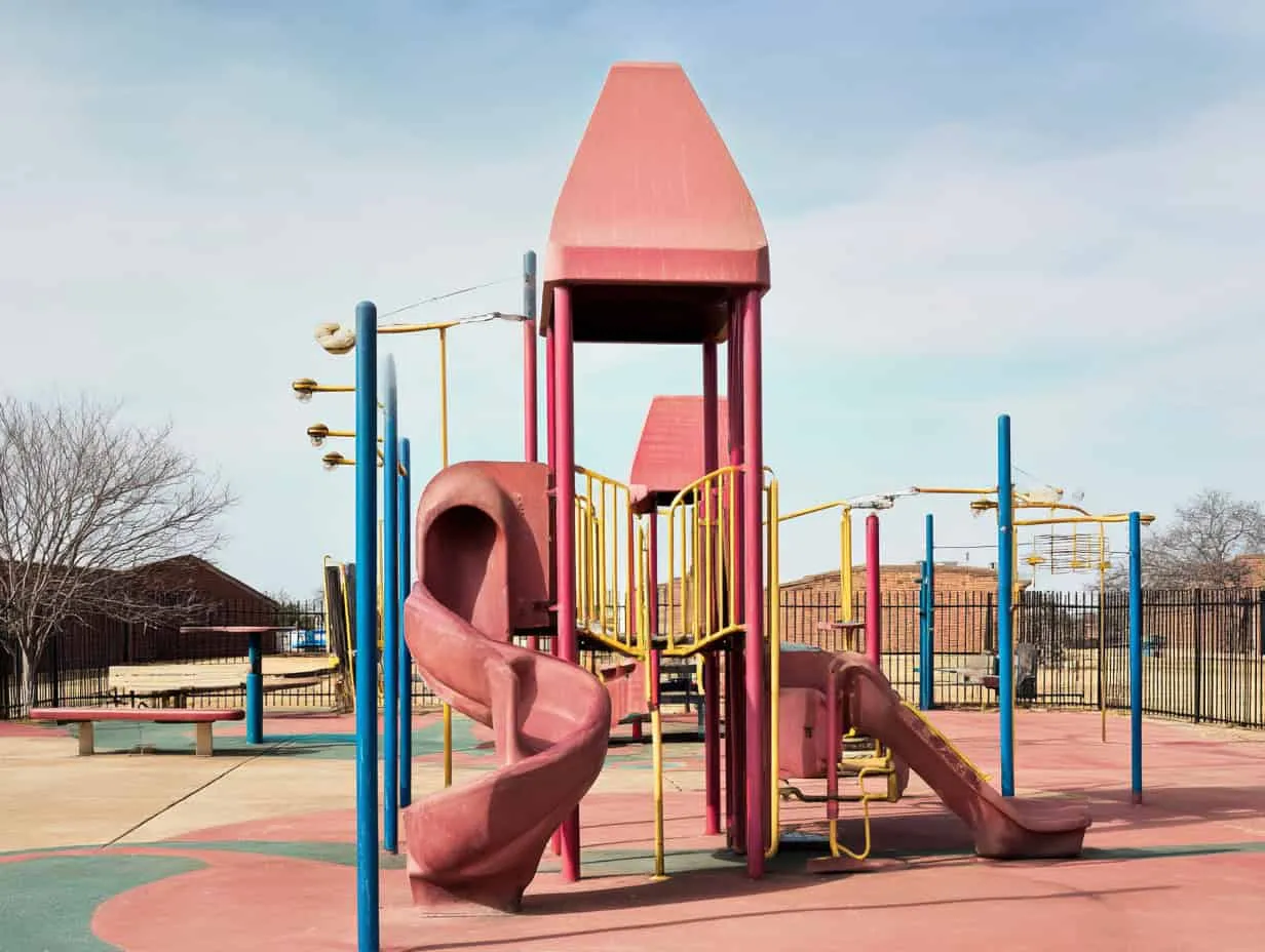 Why Miracle Recreation is the Best Choice for Early Childhood Playgrounds Colorful playground structure with slides and climbing elements, situated in an outdoor park area with a fenced perimeter and clear blue sky backdrop.