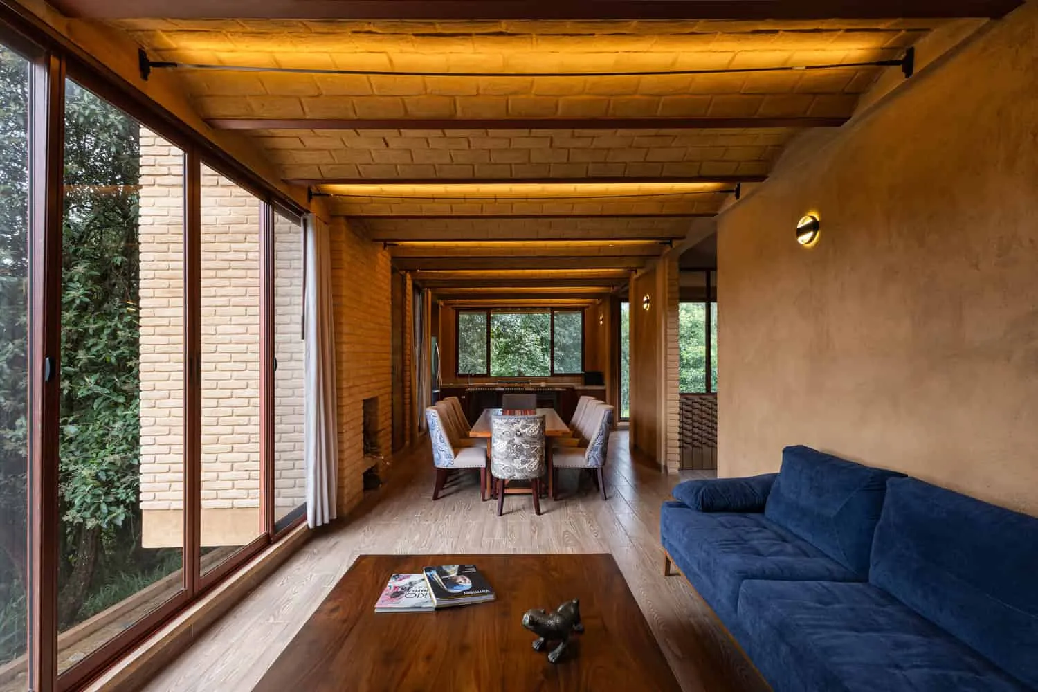 मेक्सिको के चियापास में स्थित जंगल की ओर बड़ी खिड़कियों वाला Valdez Arquitectos द्वारा डिज़ाइन किया गया The Sierra House का ओपन-प्लान लिविंग एवं डाइनिंग स्पेस
