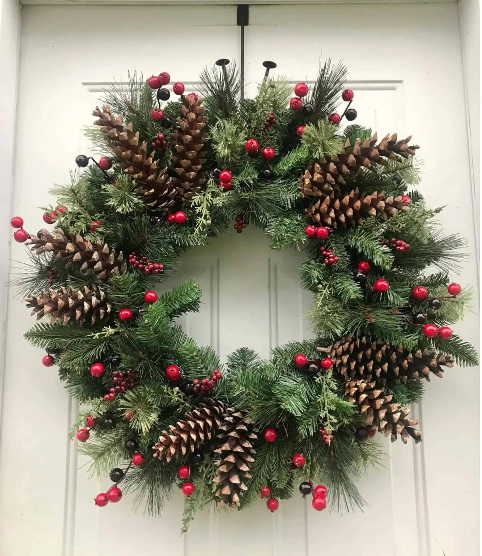 Großer Weihnachtskranz mit Kiefernzapfen und Beeren Übergroße Kiefernzapfen und rote Beeren auf einem üppigen, immergrünen Weihnachtskranz