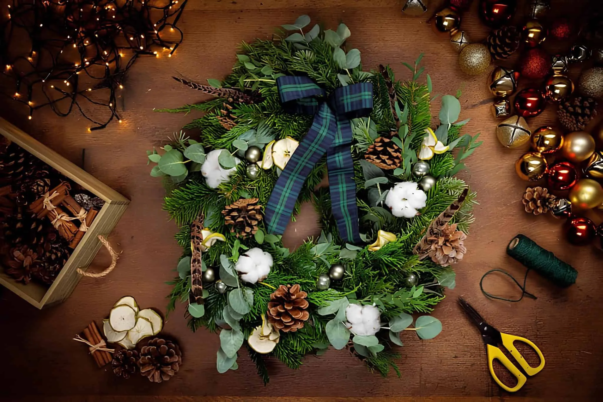 Tartan-Bogen-Weihnachtskranz aus Baumwolle und Zitrusfrüchten Weihnachtskranz mit Tartan-Bogen, Eukalyptus, Baumwollballen, Zitrusscheiben und Kiefernzapfen