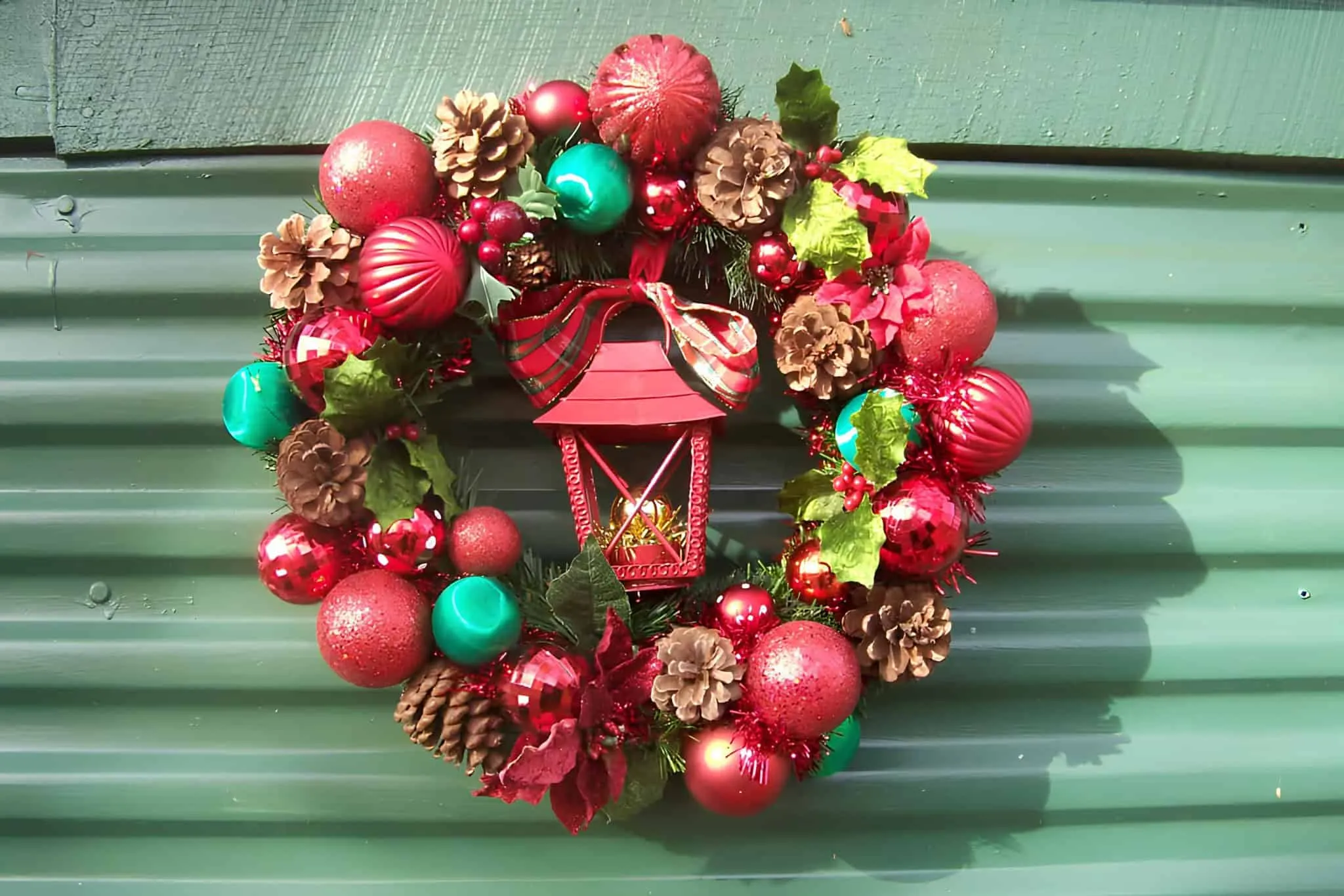 Classic Lantern Christmas Wreath Traditioneller Lanternkranz mit rotem Band, grünen und goldenen Verzierungen sowie Kiefernzapfen