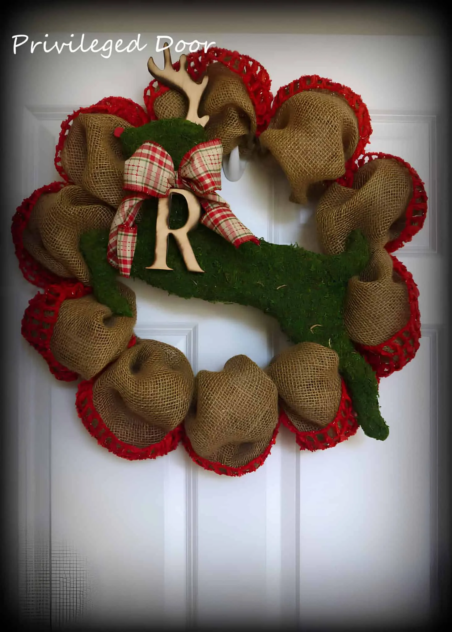 Moss Reindeer Initial Burlap Christmas Wreath Jutekranz mit roten Rändern sowie einer Silhouette eines Moosrehs mit kariertem Band und Monogramm