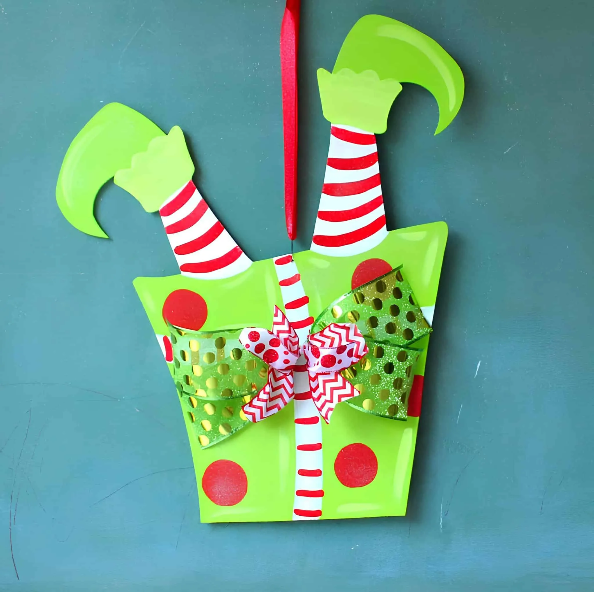 Elf Legs Gift Box Door Hanger Leuchtend grüner Türhänger für eine Geschenkbox mit gestreiften Elfenbeinen und festlichen Bändern