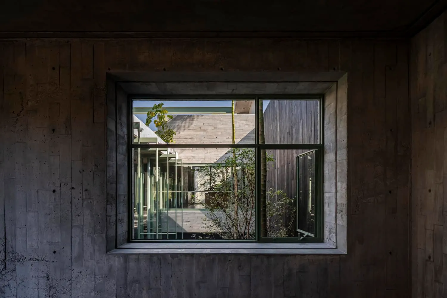 Di Frenna Arquitectos设计的Atelier窗户景观 带有黑色框架的现代混凝土窗户,可眺望室外绿植,采用极简主义建筑风格,充满自然光线,属于可持续设计理念下的当代住宅建筑,兼具城市景观美化与环保建筑特性。
