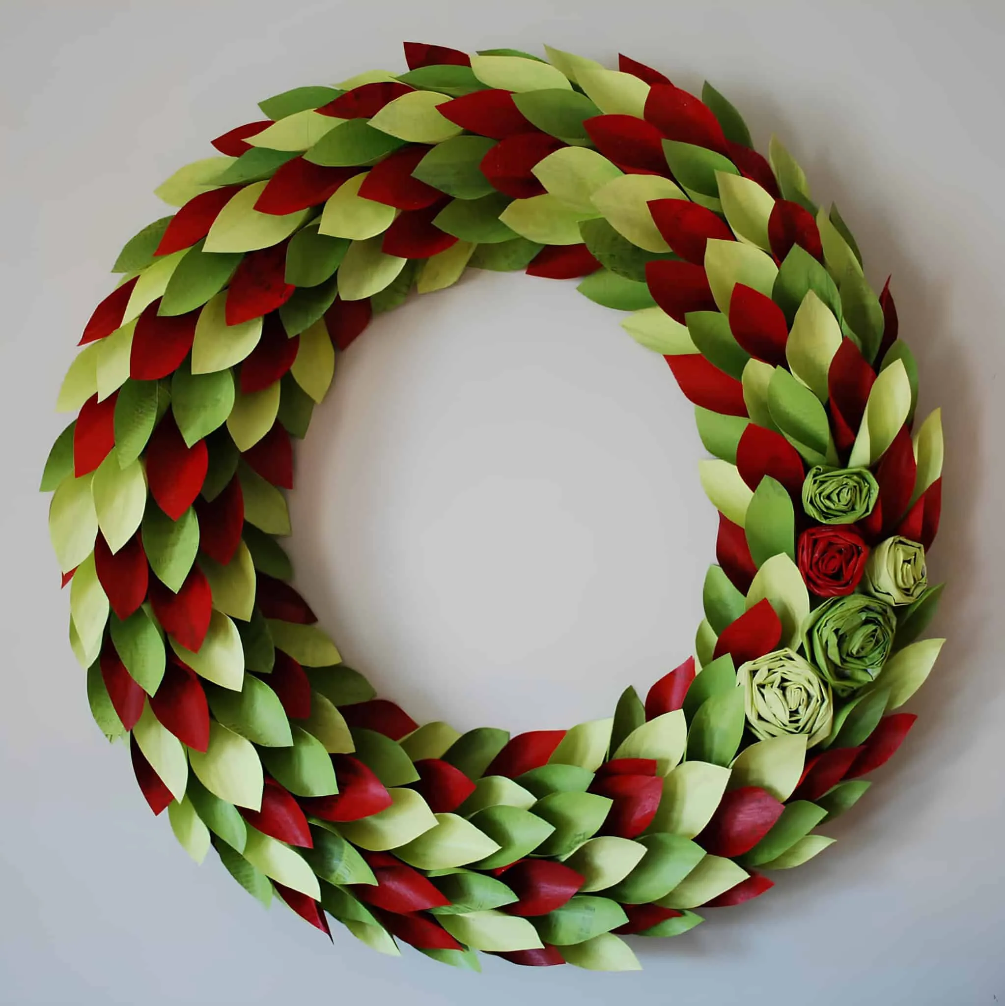 Weihnachtskranz aus roten und grünen Papierblättern Weihnachtskranz aus roten und grünen Papierblättern mit Rosettenverzierungen