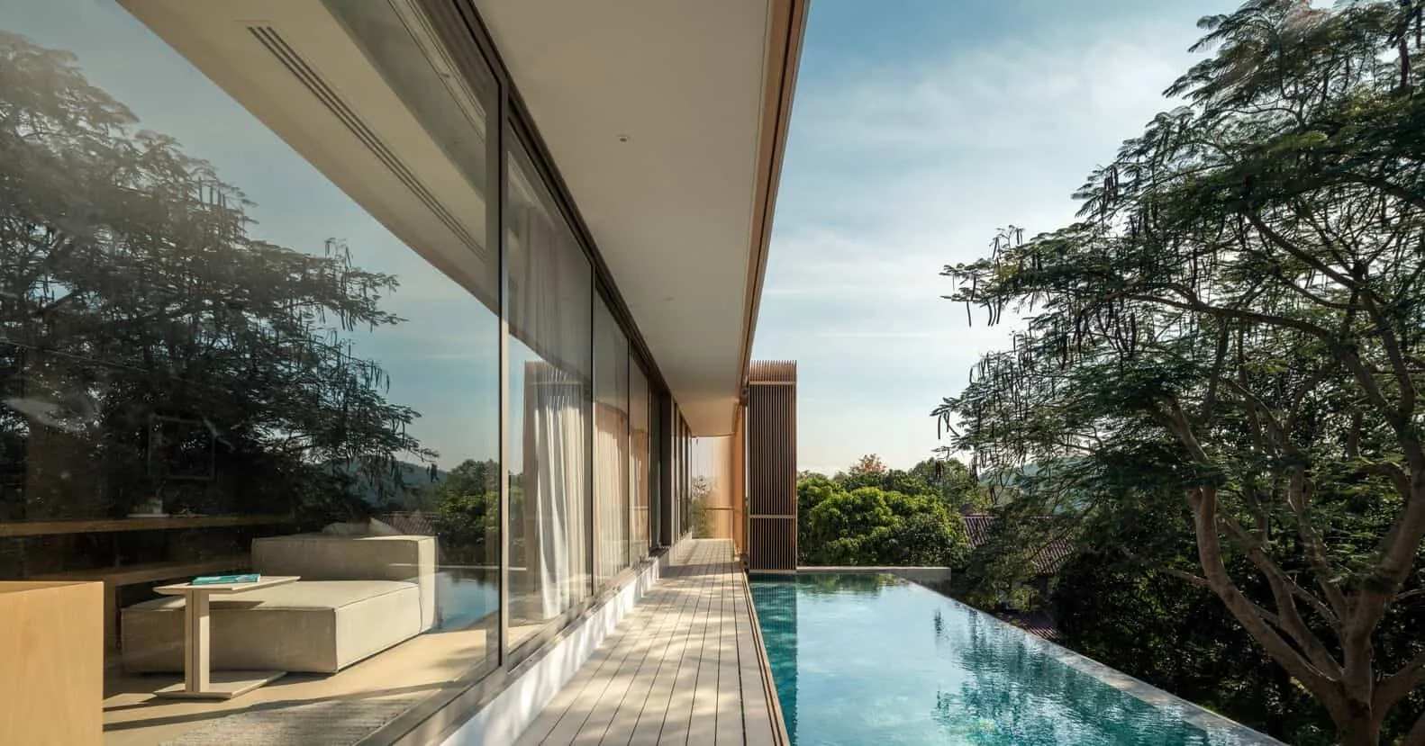 W House II Infinity Pool von IDIN Architects Ein modernes Luxushaus mit Glaswänden, Infinity-Pool und üppigen grünen Bäumen, das zeitgenössische Architektur und innovatives Design zeigt. Ideal für ein gehobenes Wohnen, das Innen- und Außenräume miteinander verbindet.