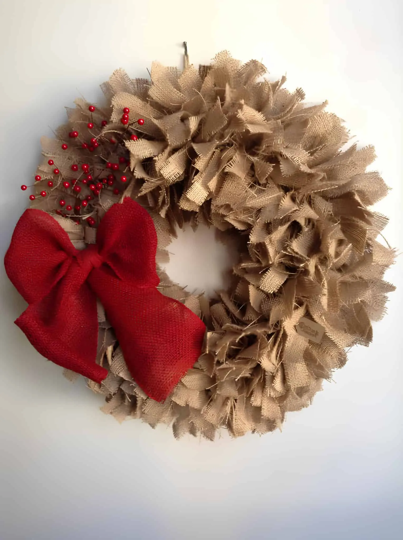 Ländlicher Leinenschmuckkranz mit roter Schleife Ländlicher Leinenschmuckkranz zum Weihnachtsfest mit roter Schleife und roten Beeren