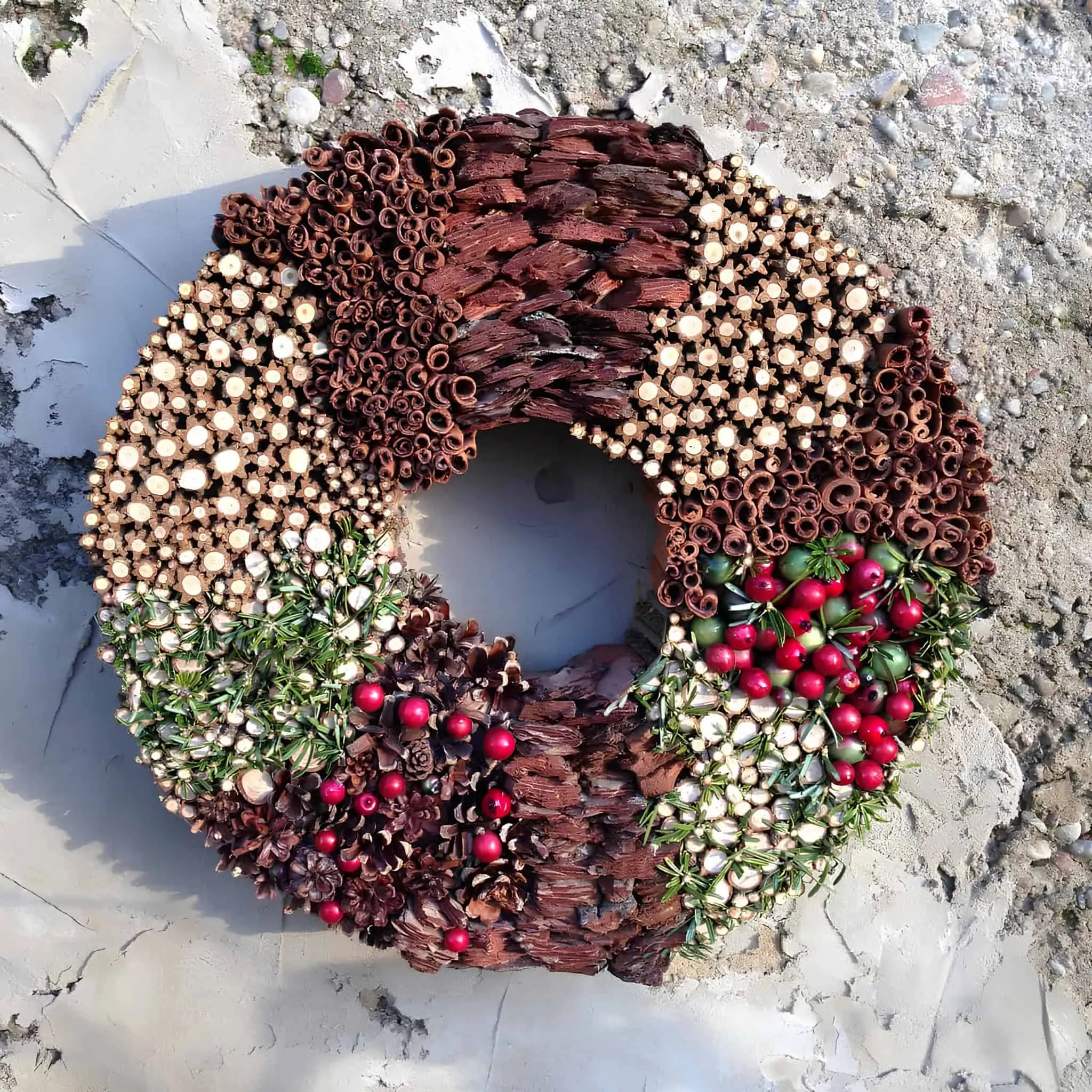 Weihnachtskranz aus natürlichem Holz und Beeren Handgefertigter natürlicher Kranz mit Rinde, Beeren, Kiefernzapfen und getrockneten Holzstreifen