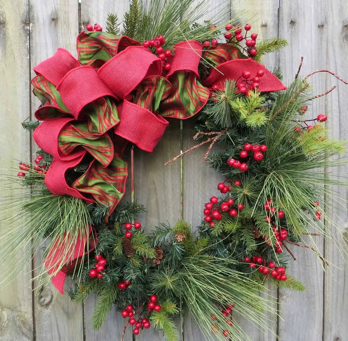 Kranz aus roten und grünen Bändern sowie Beeren Weihnachtskranz mit roten und grünen Bändern sowie Beerenbüscheln