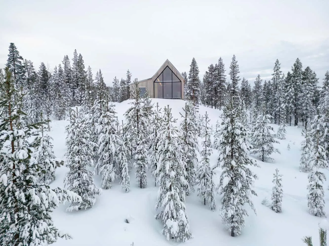 Pirinen Salo Oy拍摄的冬季背景下的山丘上的房屋 芬兰伊纳里地区被雪覆盖的森林环绕着的Pirinen Salo Oy拍摄的山丘上的房屋