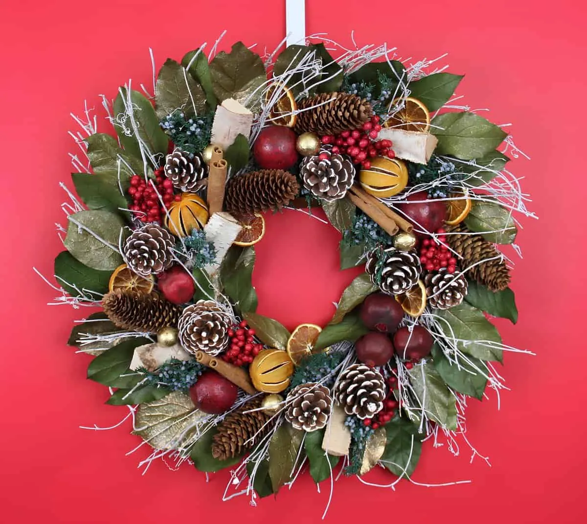 Magnolia & Pinecone Christmas Wreath Kranz aus Magnolienblättern mit bemalten Kiefernzapfen, roten Beeren, Zimtstangen und getrockneter Orange