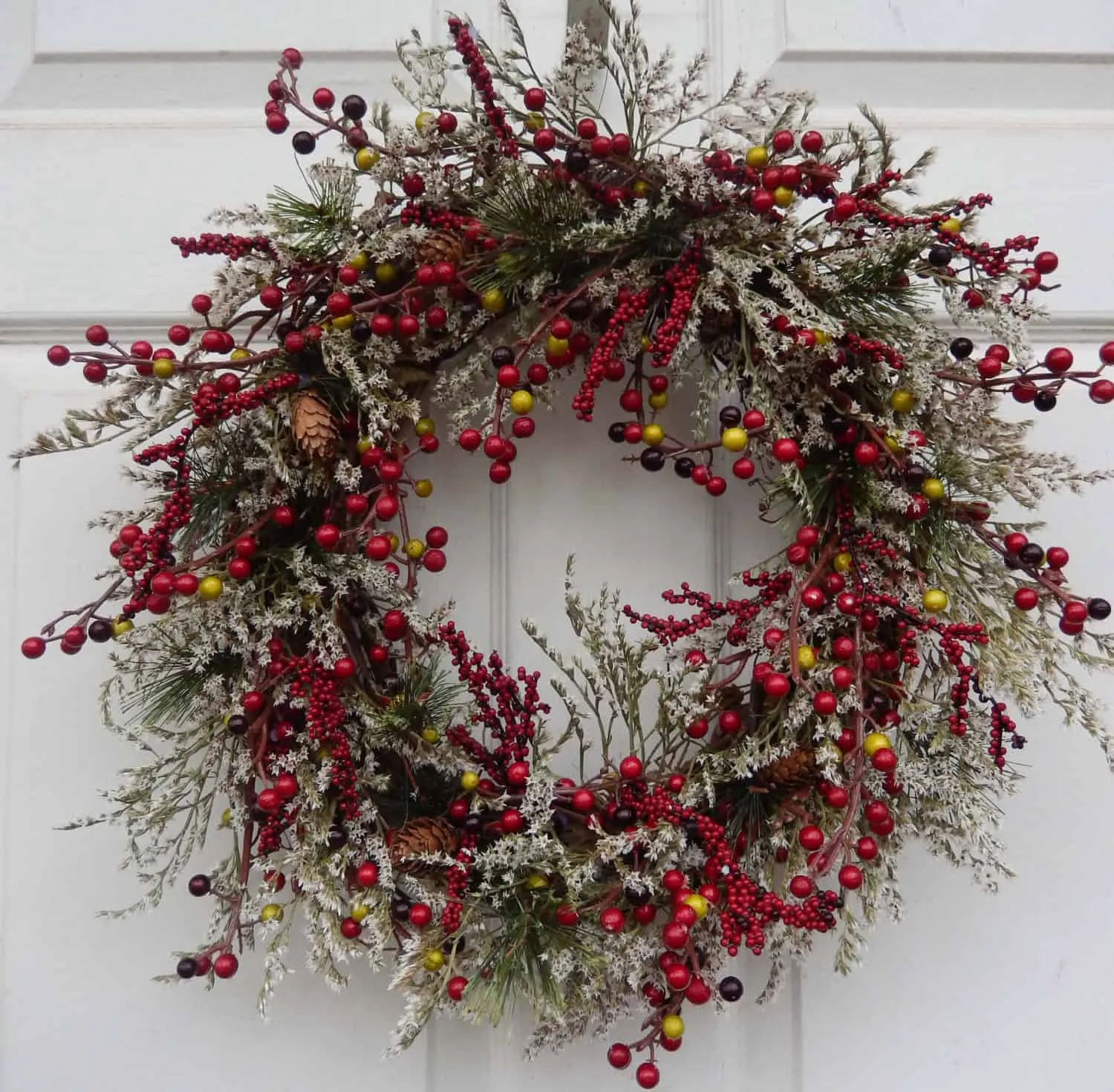 Schneeverzierter Mischberren-Weihnachtskranz Mit Schnee bedeckter Mischberren-Weihnachtskranz mit gelben Akzenten