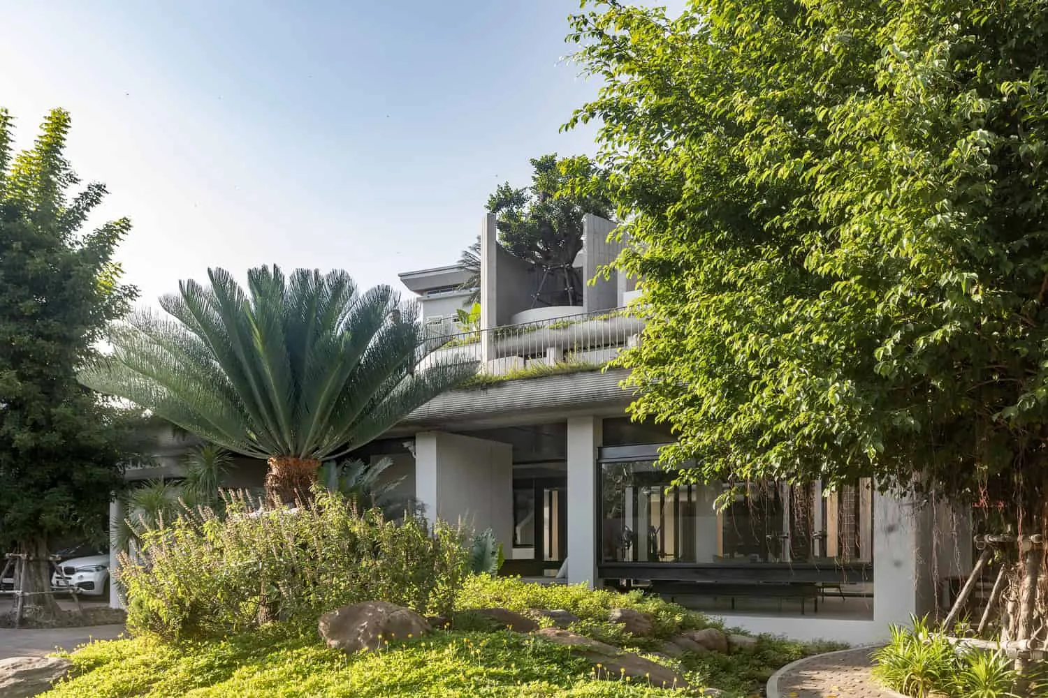Wat Bo House Gartenansicht mit Palme im Vordergrund von UAD Architects Wat Bo House von UAD Architects – Gartenansicht mit einer großen Palme im Vordergrund in Kambodscha