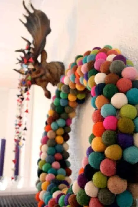 Bunter Pom-Pom-Weihnachtskranz Lebhafter, mehrfarbiger Pom-Pom-Weihnachtskranz in Nahaufnahme