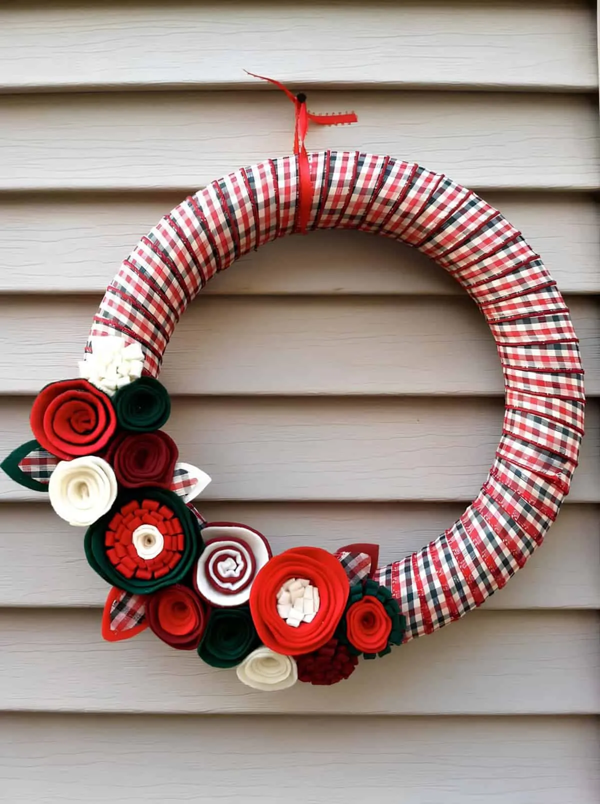 Stoffblumen-Weihnachtskranz Selbstgemachter Weihnachtskranz, eingewickelt in karierten Stoff mit roten, grünen und weißen Stoffblumen