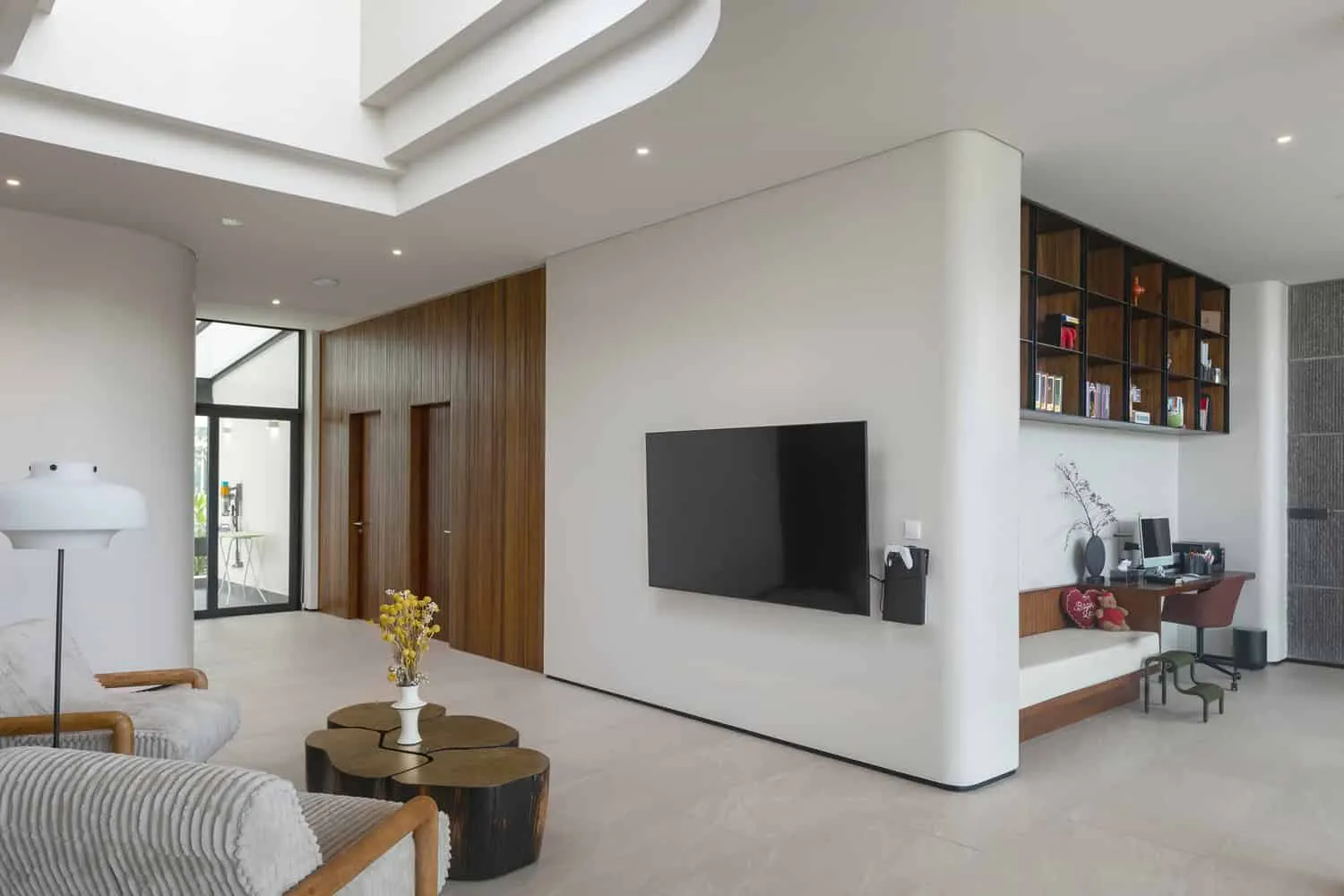 Wohnzimmer mit doppelter Höhe und TV-Wand im Wat Bo House von UAD Architects Wohnzimmer im Wat Bo House von UAD Architects mit doppelter Höhe und Stein-TV-Wand in Kambodscha