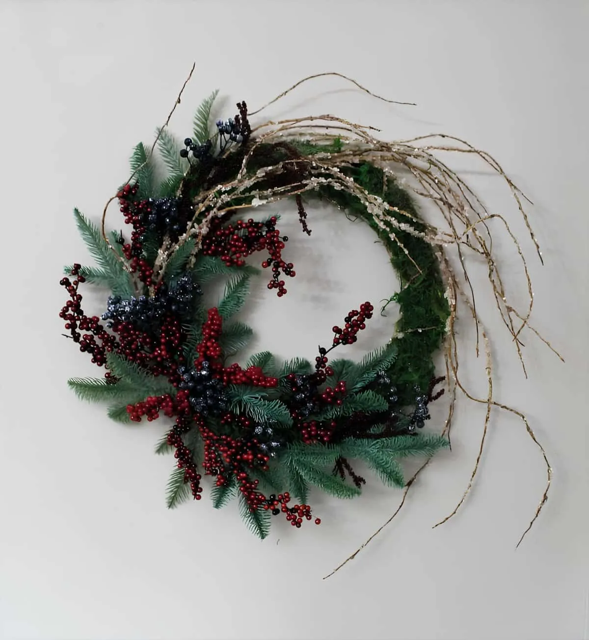 Weihnachtskranz aus wilden Zweigen und Beeren Asymmetrischer Zweigkranz mit Nadelbäumen sowie Büscheln aus roten und blauen Beeren