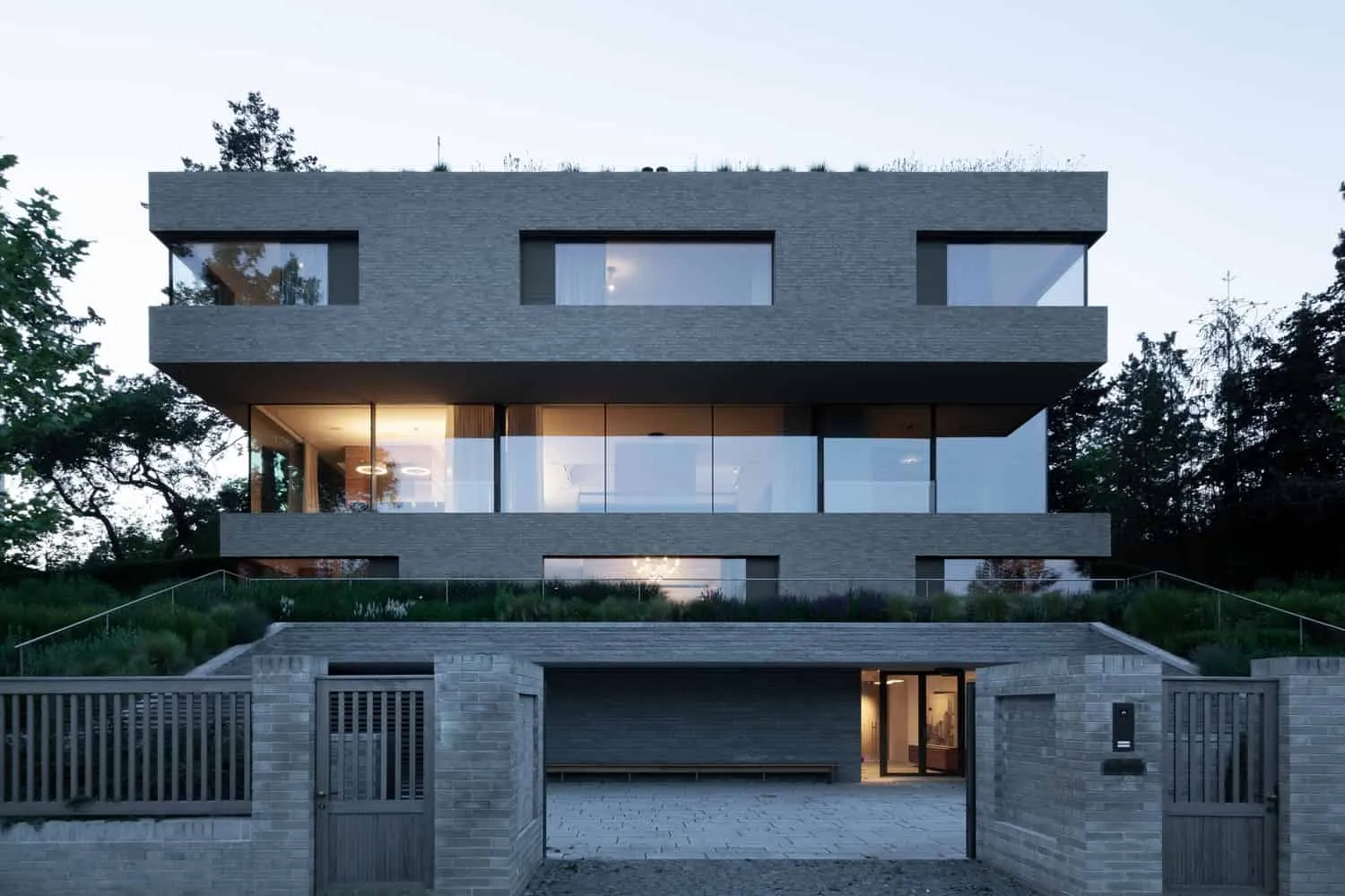 Villa Vista – Ansicht von der Straße mit Tor und Terrassenanlage, entworfen von Znameni Ctyr Architekti Villa Vista von Znameni Ctyr Architekti, Ansicht zur Straße mit Ziegeltor und terrassiertem Garten