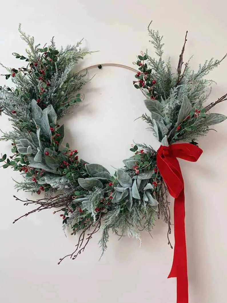 Weihnachtskranz mit roter Schleife und Beeren Eleganter Feiertagskranz mit roter Schleife und winterlichen Blättern
