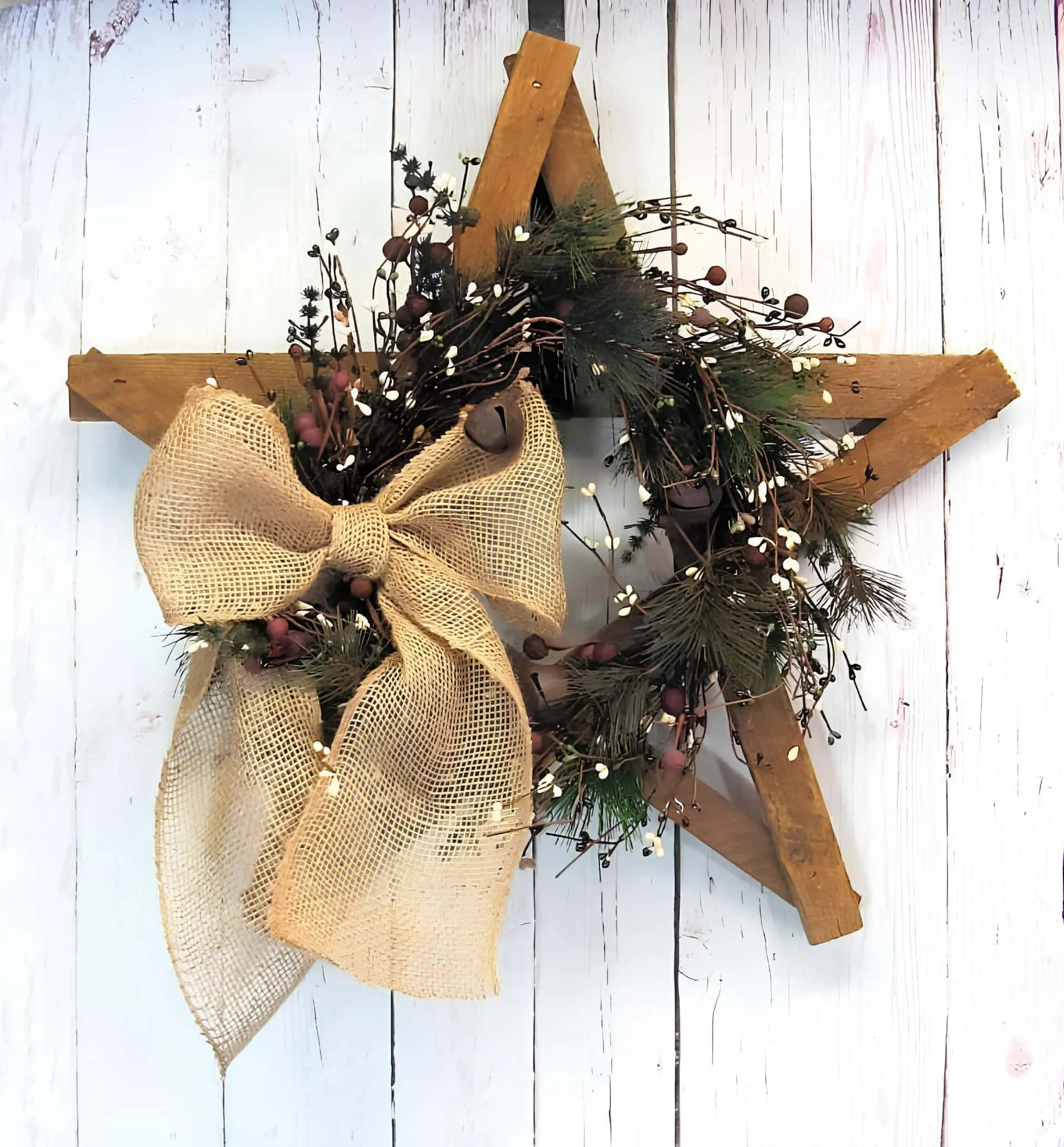 Ländliche Stern-Weihnachtskrone mit Leinenschleife Ländliche Holzsternkrone mit Wintergrün und einer Leinenschleife