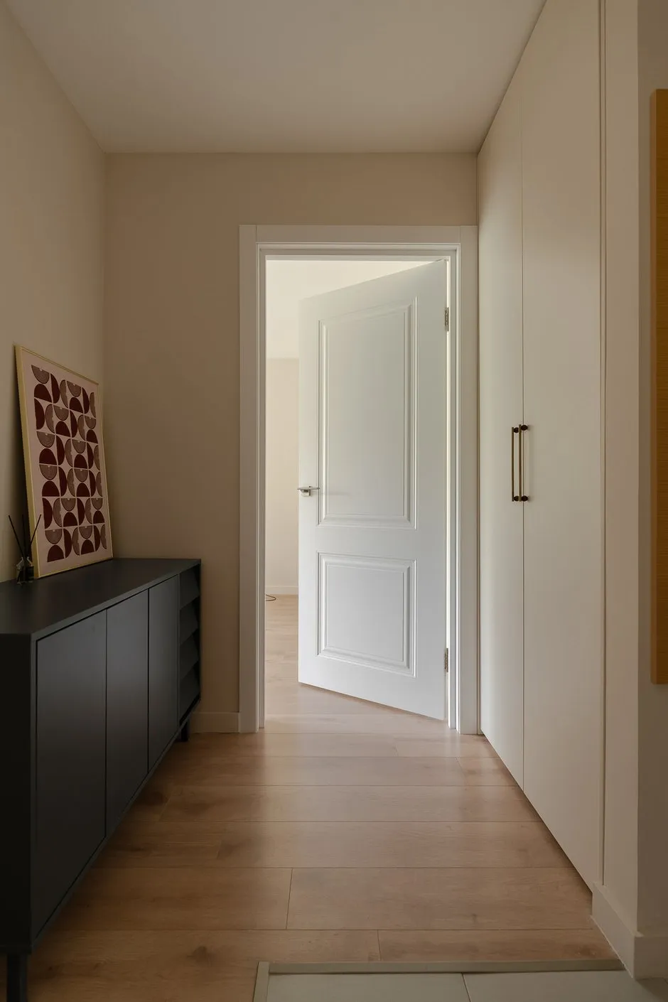 Intérieur minimaliste d’entrée. La combinaison de bois clair, de meubles intégrés et de mobilier sobre crée une atmosphère chaleureuse.