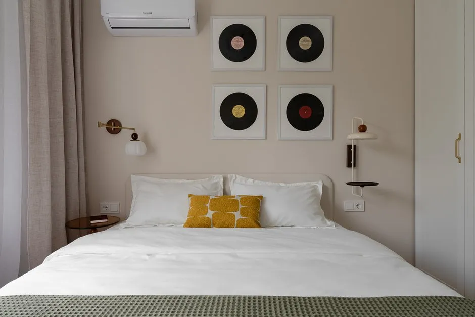 Intérieur minimaliste de chambre à coucher. Éclairage bien pensé, textiles accentués et éléments décoratifs sur les murs.