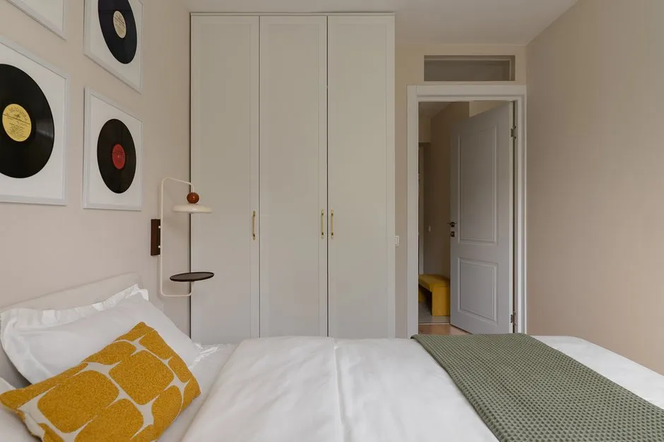 Intérieur scandinave de chambre à coucher. Des façades blanches épurées des armoires s’associent à des textiles et éléments décoratifs voyants.