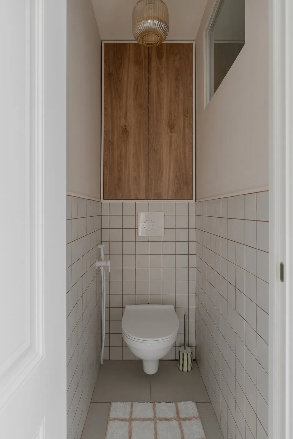 Intérieur minimaliste de salle de bain. La combinaison de carrelage clair, de bois et de solutions fonctionnelles crée une atmosphère chaleureuse.